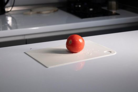 cutting white plastic board with a tomato on it. cooking process. High quality photo