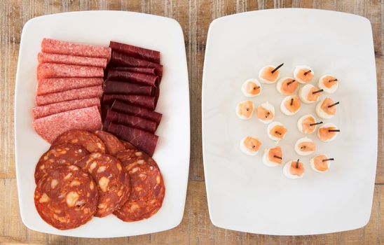 Party appetizer platters with salami, bresaola,  chorizo, and smoked salmon with cream cheese.