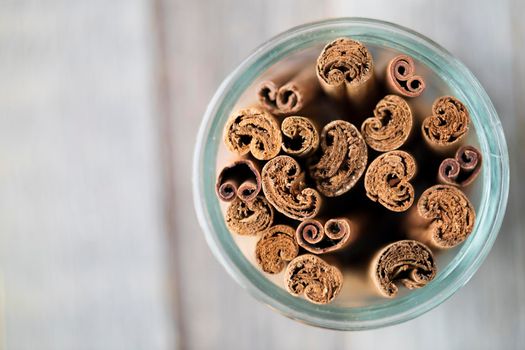 Cinnamon sticks in a glass jar from above with shallow depth of field and copy space.