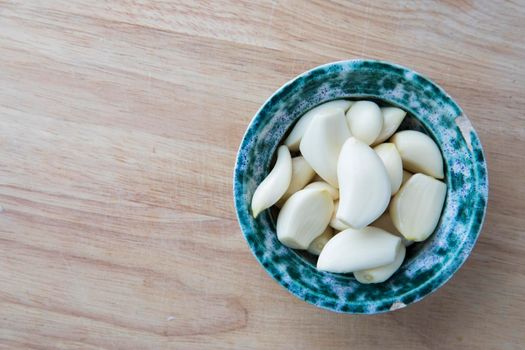 Peeled garlic cloves in bowl on cutting board viewed from directly above.