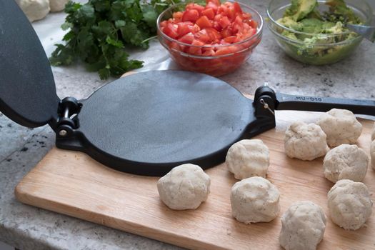 Masa harina tortilla dough on cutting board with tortilla press