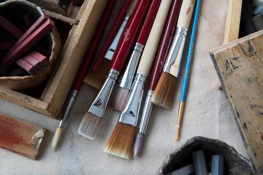 Artists paint brushes and other supplies on canvas