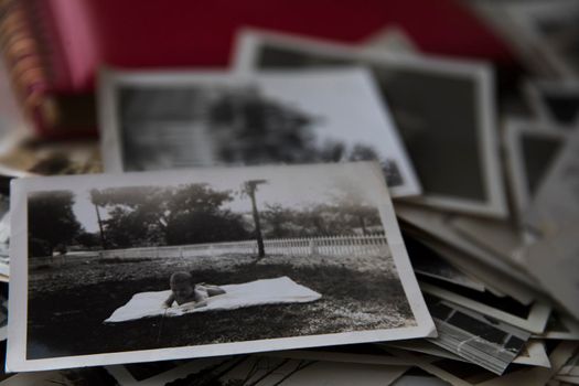 Stack of old photos with photo of baby on the top.