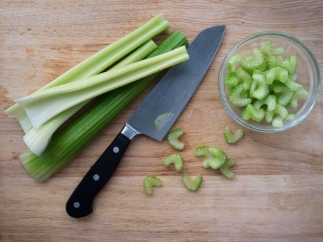 Celery stalks and slices with knife on cutting board