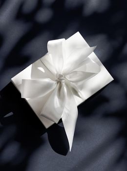 Anniversary celebration, shop sale promotion and luxe surprise concept - Luxury holiday white gift box with silk ribbon and bow on black background, luxe wedding or birthday present