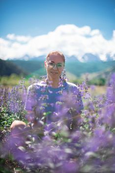 Happy young woman in beautiful wild pink and purple flowers field in summer Altai mountains