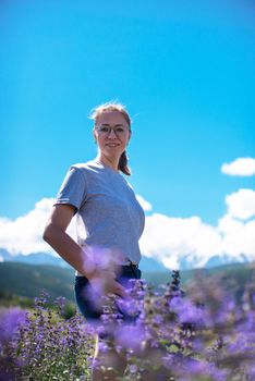 Happy young woman in beautiful wild pink and purple flowers field in summer Altai mountains