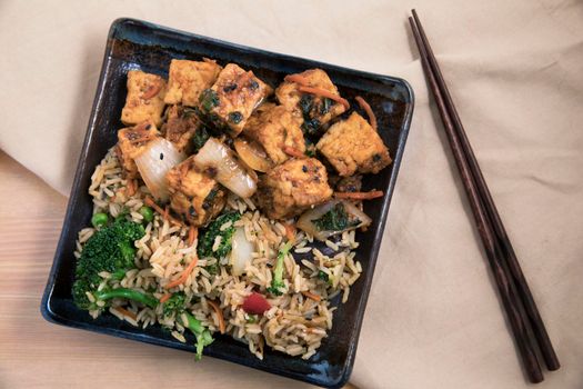 Fried tofu with rice and vegetable stir fry vegan asian meal.