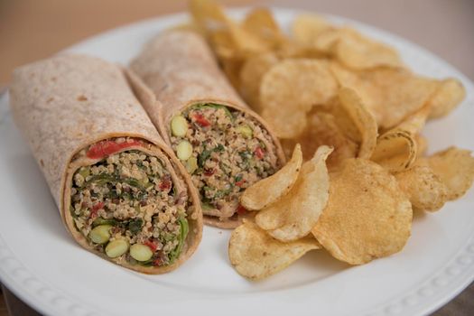 Vegan quinoa wrap served with chips.