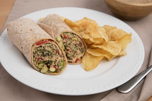 Vegan quinoa wrap served with chips.
