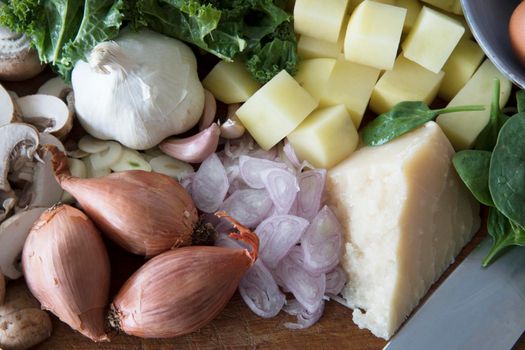 Fresh ingredients with parmesan, shallots, garlic, mushrooms, potatoes and kale.