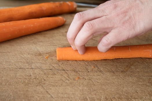 Knifee skilles cutting a carrot: demonstrating the correct way to hold fingers when cutting food.