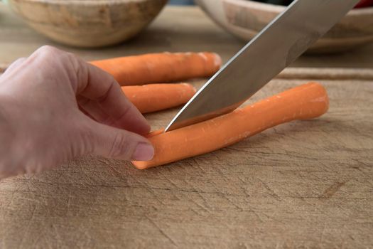 Knife skills cutting slicing carrot in half safely cutting away from fingers stabilizing food.