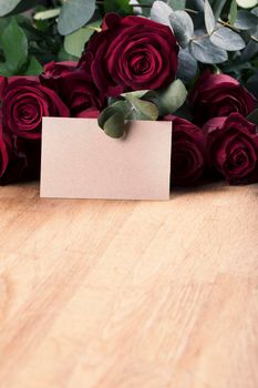 Vertical red roses on table with blank card for your message