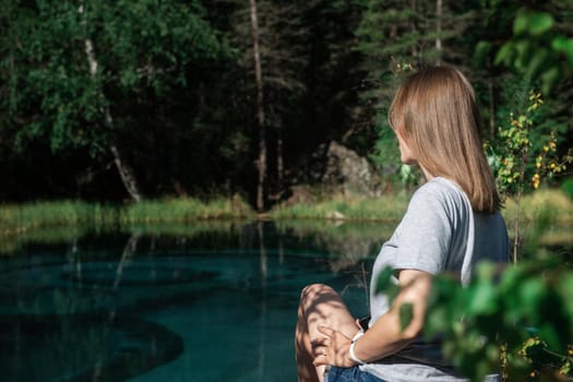 Woman resting at mountain lake in summer, Altai mountains