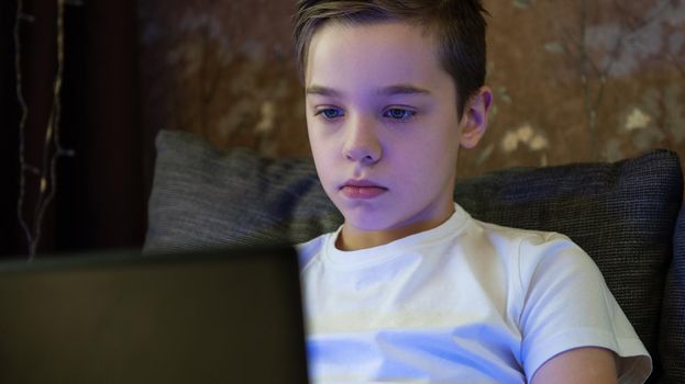 Kid boy or teen learning at home on laptop for school. Adorable child making homework and using notebook. Home schooling concept.