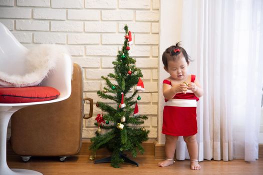 Full Length Of Cute Baby Girl Wearing Santa Costume While Sitting With Christmas Decorations