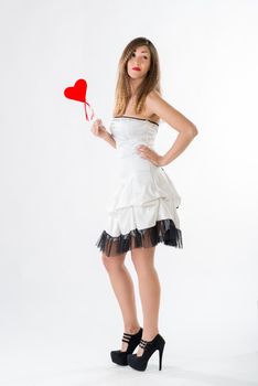 Beautiful girl standing and holding red heart. Looking at camera.