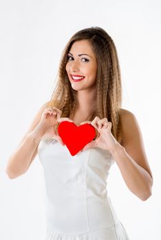 Beautiful smiling girl standing and holding red heart. Looking at camera.