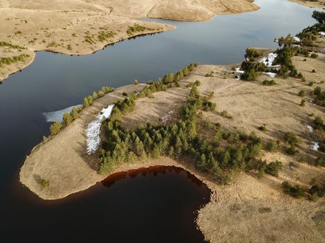 View from drone on mountain river crossing through desert landscape with rare forest.