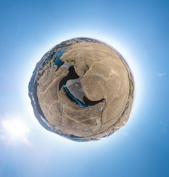 Spherical panorama of a little planet with mountains lakes and rivers on a blue sky background.