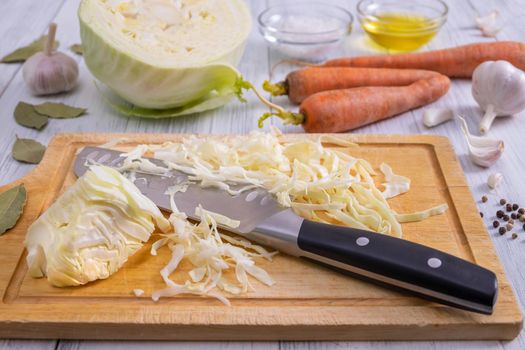 Close-up of a kitchen workspace with the process of shredding white cabbage and the ingredients for its fermentation or cooking