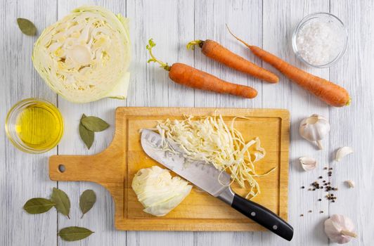 Top view of kitchen workspace with white cabbage shredding process and ingredients for fermentation or cooking
