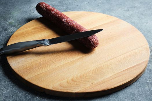 Salami and knife on a cutting board.