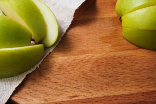 sliced green apple on wooden cutting board.