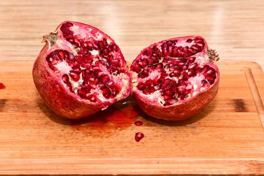 Halved red ripe pomegranate fruits on a wooden board. Natural pomegranate closeup.