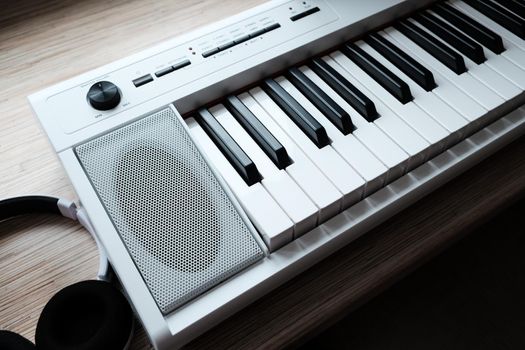 white music keyboard with headphones on wooden table.