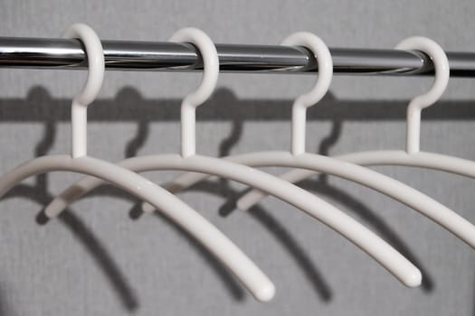 close-up of many white plastic clothes hanger on rod with shadow.