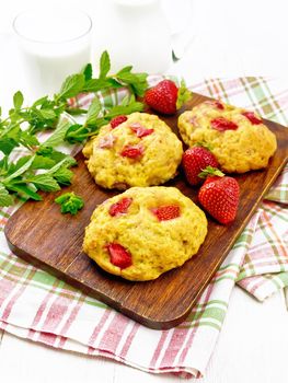 Strawberry scones with berries on a brown plate on a napkin, mint sprigs on the background of light wooden board