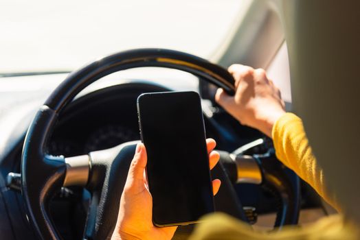 Asian woman inside a car and using a hand holding mobile smartphone blank screen while driving the car in the morning during going to work on highway, Transportation and vehicle concept