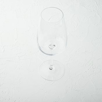 Clean wine glass set, square format, on white stone background