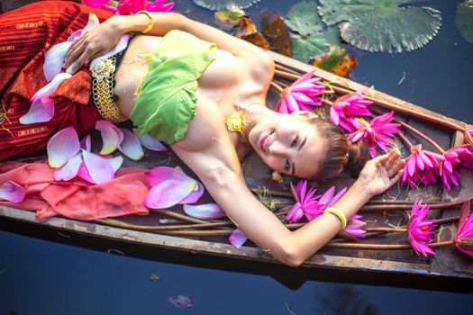 Young Asian women in Traditional dress in the boat and pink lotus flowers in the pond.Beautiful girls in traditional costume.Thai. Ayutthaya, elegance.