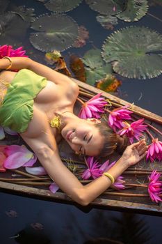 Young Asian women in Traditional dress in the boat and pink lotus flowers in the pond.Beautiful girls in traditional costume.Thai. Ayutthaya, elegance.