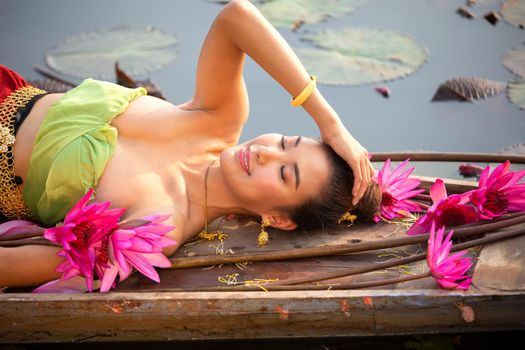 Young Asian women in Traditional dress in the boat and pink lotus flowers in the pond.Beautiful girls in traditional costume.Thai. Ayutthaya, elegance.