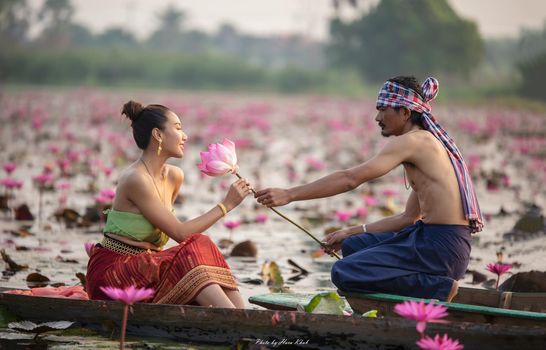 Young Asian women in Traditional dress in the boat and pink lotus flowers in the pond.Beautiful girls in traditional costume.Thai. Ayutthaya, elegance.