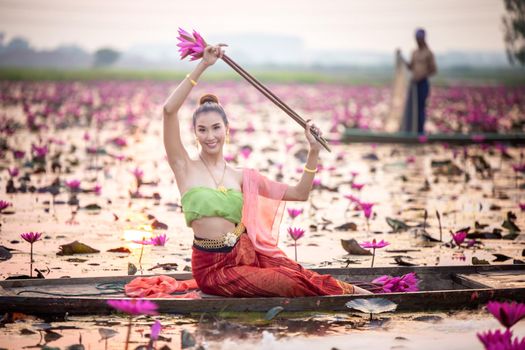 Young Asian women in Traditional dress in the boat and pink lotus flowers in the pond.Beautiful girls in traditional costume.Thai. Ayutthaya, elegance.