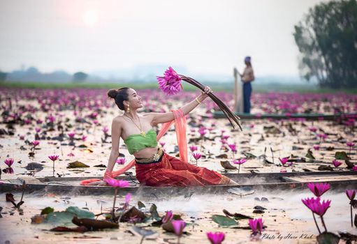 Young Asian women in Traditional dress in the boat and pink lotus flowers in the pond.Beautiful girls in traditional costume.Thai. Ayutthaya, elegance.