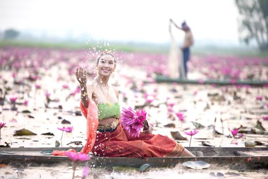 Young Asian women in Traditional dress in the boat and pink lotus flowers in the pond.Beautiful girls in traditional costume.Thai. Ayutthaya, elegance.