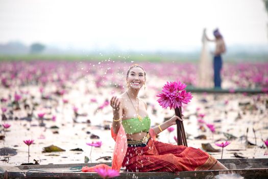 Young Asian women in Traditional dress in the boat and pink lotus flowers in the pond.Beautiful girls in traditional costume.Thai. Ayutthaya, elegance.