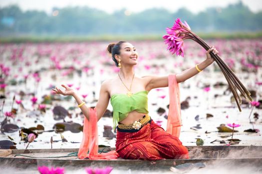 Young Asian women in Traditional dress in the boat and pink lotus flowers in the pond.Beautiful girls in traditional costume.Thai. Ayutthaya, elegance.