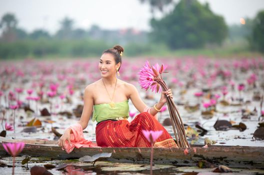 Young Asian women in Traditional dress in the boat and pink lotus flowers in the pond.Beautiful girls in traditional costume.Thai. Ayutthaya, elegance.