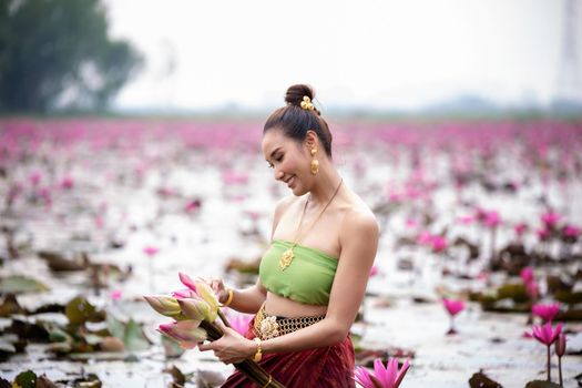 Young Asian women in Traditional dress in the boat and pink lotus flowers in the pond.Beautiful girls in traditional costume.Thai. Ayutthaya, elegance.