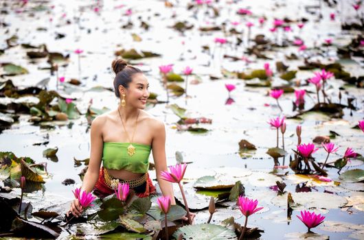 Young Asian women in Traditional dress in the boat and pink lotus flowers in the pond.Beautiful girls in traditional costume.Thai. Ayutthaya, elegance.