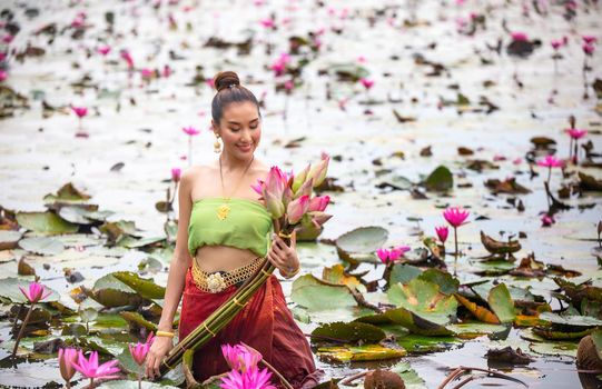 Young Asian women in Traditional dress in the boat and pink lotus flowers in the pond.Beautiful girls in traditional costume.Thai. Ayutthaya, elegance.