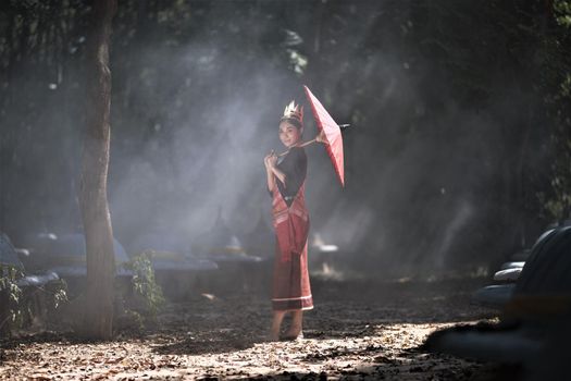 Beautiful young Asian woman dressed in traditional native dress and elephant in forest of village Surin Thailand	
