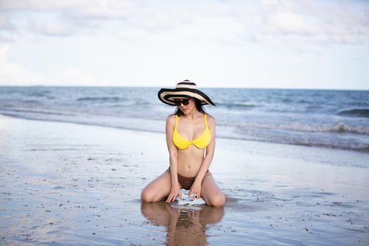 Beautiful young woman in sexy bikini on sand at sea beach.